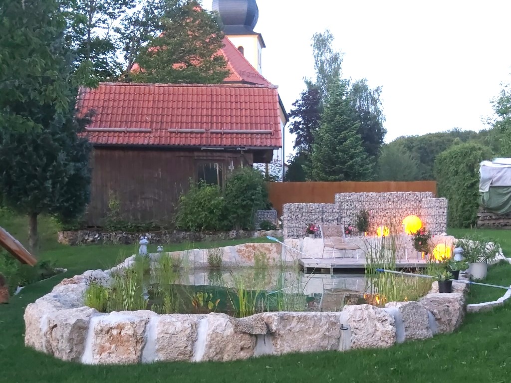 Schwimmteich mit massiver Steinumrandung mit schwebender Terrasse und harmonisches Licht